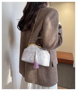 Détail du sac fermoir brodé avec jacquard floral en soie et pendentif à pompon
