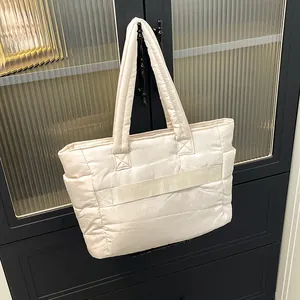 Close-up of cream quilted puffer tote bag hanging on a dark cabinet handle