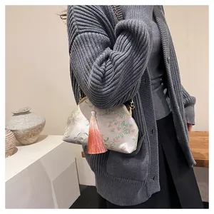 Détail de broderie florale sur sac bandoulière en soie avec pompon rose et chaîne