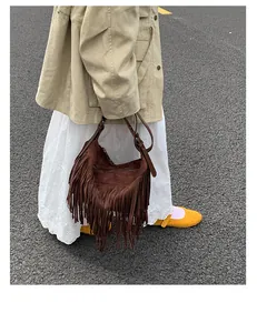 Street style shot of a brown suede hobo bag with long fringes and bohemian aesthetic