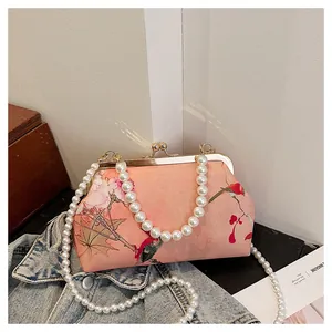 Macro detail of Chinese style floral print clutch bag with pearl handle and metal clasp