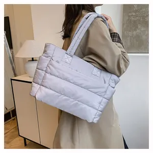 Detailed view of light gray quilted puffer tote bag with thick padded straps and stitching