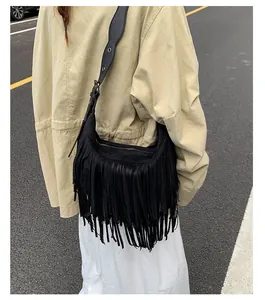 Close-up of black bohemian suede crossbody bag featuring long fringe and metal zipper details