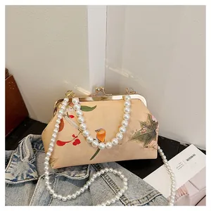 Detail of vintage floral kiss lock bag with large pearl handle and metal hardware