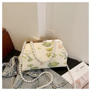 Detailed shot of vintage lotus print bag with pearl chains on denim fabric