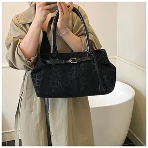 Détail du sac cabas léopard noir avec boucle dorée sur une tenue de trench-coat