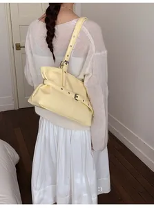 Détail du sac cabas jaune clair en cuir ciré avec boucle sur l'épaule d'un modèle