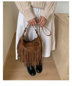 Bohemian caramel brown suede tassel crossbody bag shown on a model with retro vibes