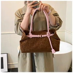 Détail du sac cabas léopard avec anses roses et boucles dorées sur un trench-coat élégant