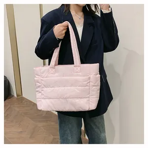 Detail of pink quilted down-filled tote bag with glossy nylon texture and soft padded handle