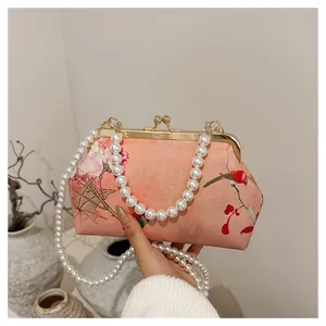 Detail of pink satin evening bag with floral bird print and dual pearl chain straps