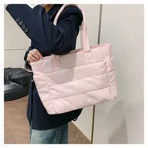 Detail of pink quilted puffer tote bag showing side pocket and soft padded texture