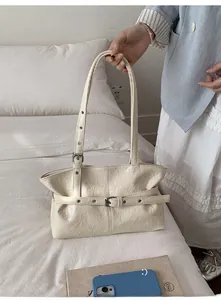 Détail de la texture en cuir ciré plissé et de la boucle sur ce sac cabas couleur crème