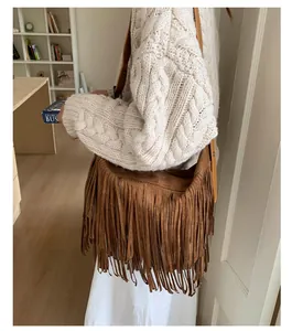 Detail of brown suede crossbody bag with long tassels and leather strap on model