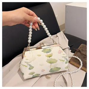 Detail of embroidered lotus handbag featuring double pearl chain and vintage metal clasp
