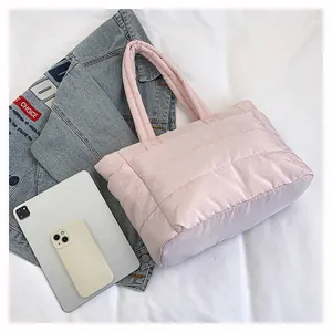 Flat lay of a pink quilted tote bag with a denim jacket and gadgets for travel