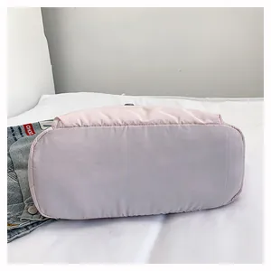 Detail view of the wide flat bottom and stitching of the pink nylon tote bag