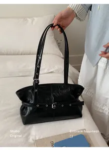 Détail du sac cabas en cuir ciré noir avec œillets métalliques argentés et sangle décorative