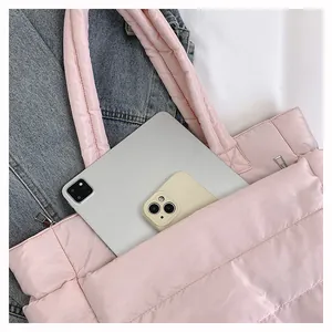 Detailed view of pink quilted tote bag showing tablet and phone storage in front pocket