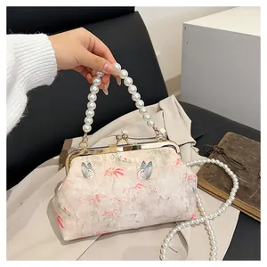 Close-up of vintage floral evening bag with pearl handle and butterfly print fabric