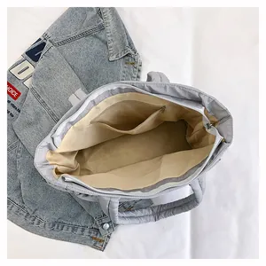 Detail view of the spacious inner compartment and zip pocket of the grey quilted tote bag