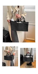Close-up of black quilted tote bag with vertical stitching and interior dividers