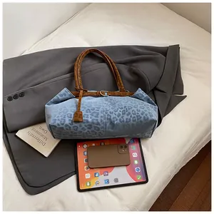 Détail du sac cabas léopard bleu avec anses en cuir marron et boucle dorée chic