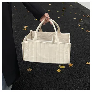 Detailed outdoor shot of a cream quilted tote bag showing its multi-compartment interior