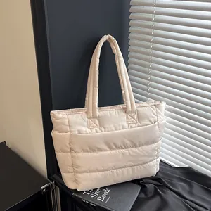 Detail of beige quilted tote bag showing side pockets and padded polyester texture