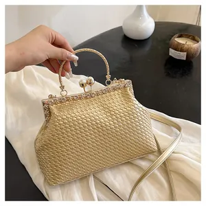 Dettaglio della pochette intrecciata dorata con strass e manico circolare in metallo