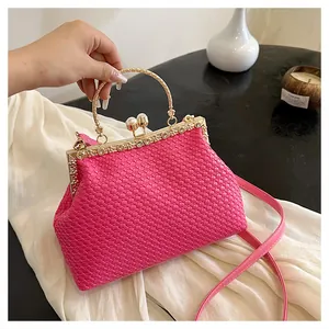 Dettaglio borsa da sera intrecciata rosa con manico dorato e finiture in strass luccicanti