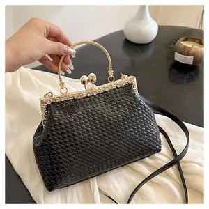 Dettaglio di pochette nera intrecciata con finiture dorate e chiusura a perla
