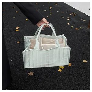 Detail view of mint green quilted tote bag showing multiple internal storage compartments