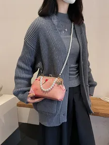 Pink floral frame bag with large pearl chain strap, shown styled with casual knitwear