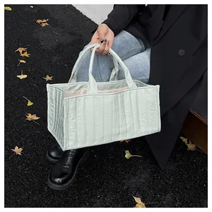 Close-up of mint green quilted tote bag with vertical stitching and top handles