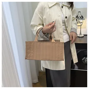 Detail of vertical quilted tote bag in khaki nylon showing rectangular structure and handles