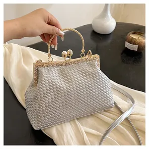 Dettaglio borsa da sera intrecciata con cornice dorata con strass e chiusura a perle
