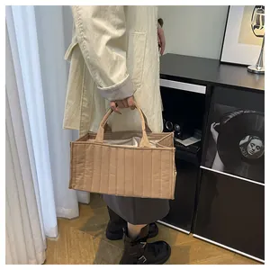 Detail of light khaki quilted tote bag featuring soft vertical stitching and double handles