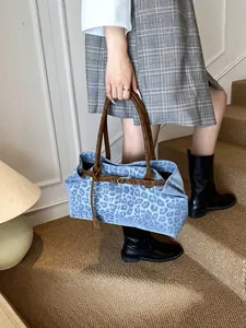 Sac fourre-tout léopard bleu avec poignées en cuir marron et sangle à boucle sur un modèle