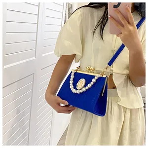 Détail d'un sac à main plissé bleu avec chaîne de perles et camée rétro en relief