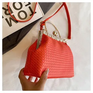 Dettaglio ravvicinato della pochette intrecciata arancione con manico in strass e chiusura