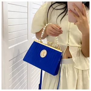 Détail du sac plissé bleu Klein avec poignée en perles et emblème ovale en relief rétro