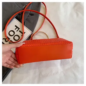 Dettaglio della borsa intrecciata arancione con manico tondo in metallo e tracolla in pelle
