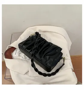 Detail of black pleated cloud bag with braided handle and gold metal clip hardware