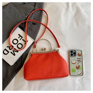 Dettaglio macro della clutch intrecciata arancione con strass e chiusura in metallo