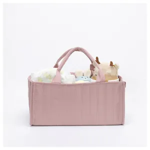 Pink quilted baby organizer tote bag with handles showing diapers and soft toys inside