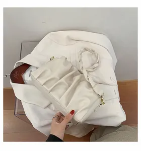 Close-up of a white pleated cloud bag with braided handle on a white blazer