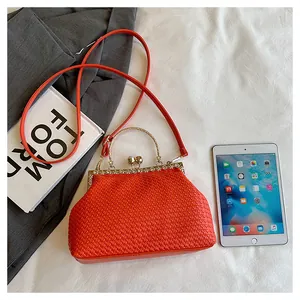 Dettaglio borsa da sera intrecciata arancione con cornice oro e chiusura strass