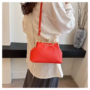 Dettaglio borsa da sera intrecciata rossa con chiusura in strass dorati e tracolla in pelle