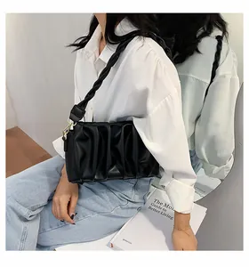 Close-up of black pleated PU leather handbag with unique woven shoulder strap and metal buckle